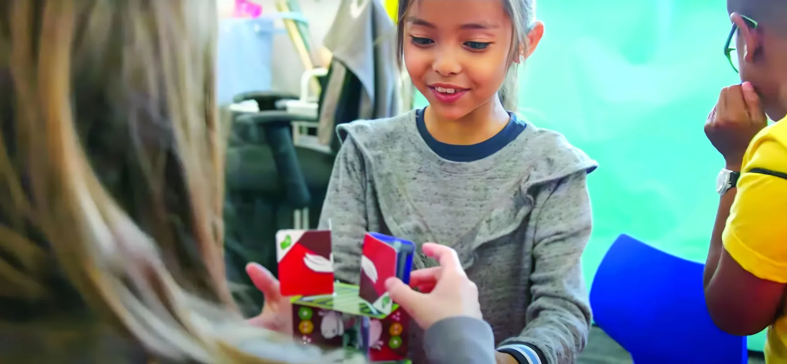 A student smiles as she places a game card down during a QUEST challenge